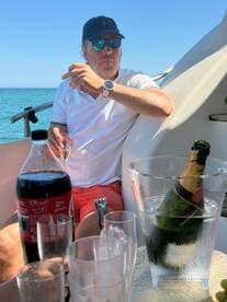 A man enjoys drinks on a boat, featuring champagne and cocktails, perfect for a relaxing day on the water.