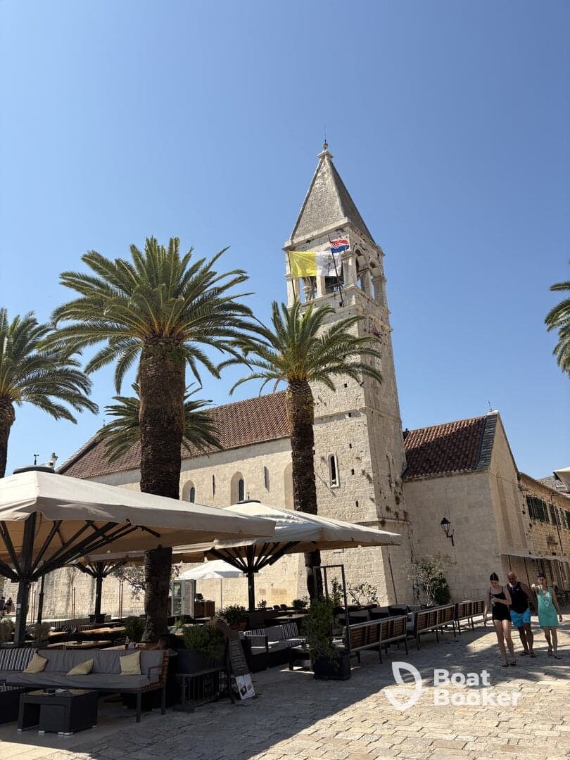 A scenic view of a historic building with palm trees and outdoor seating, capturing the essence of a vibrant coastal town.