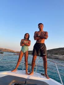 A young boy and girl pose confidently on the bow of a boat, capturing a fun moment under the sunset — perfect for summer adventures on the water.