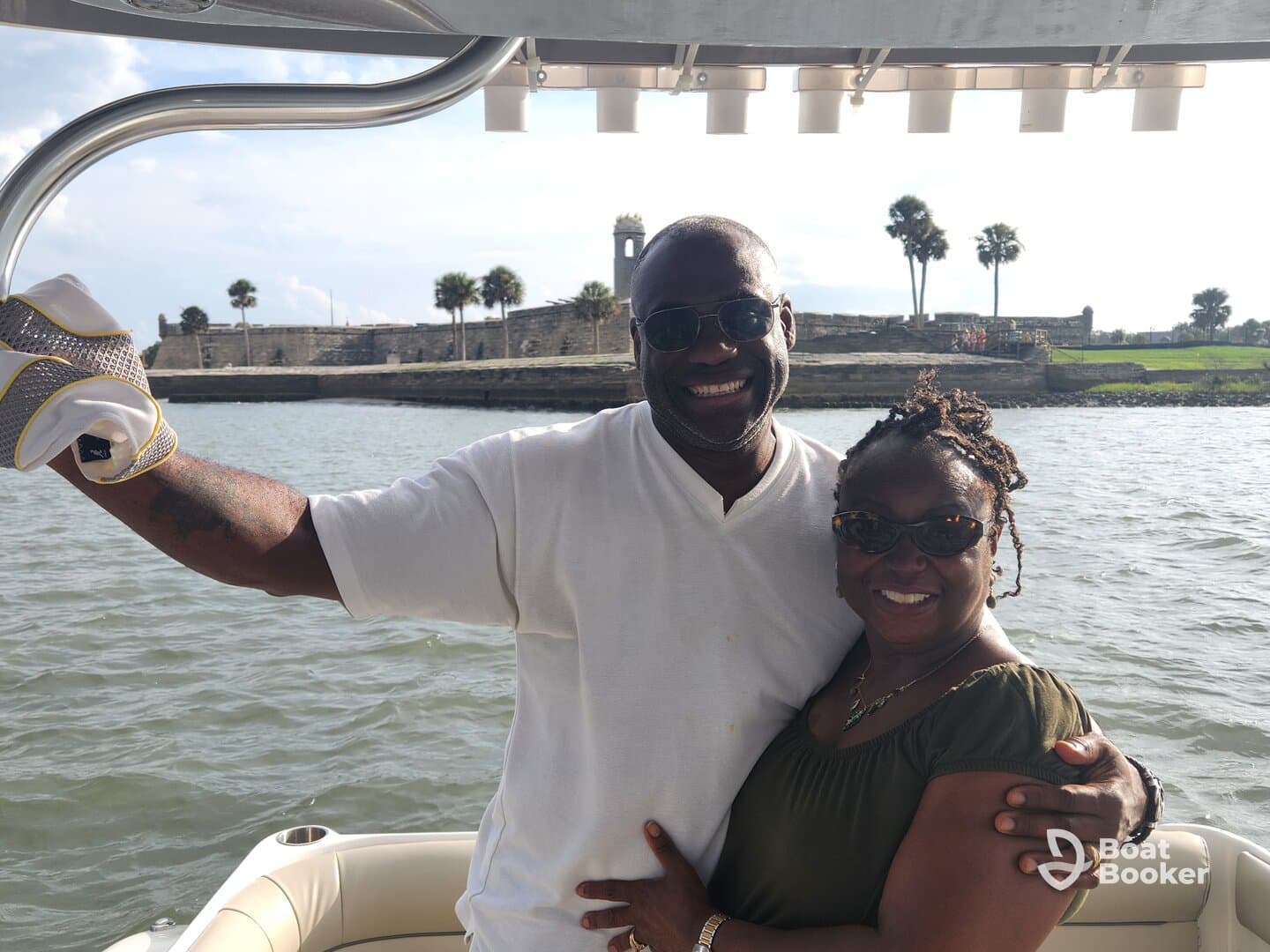 A joyful couple poses together on a boat, enjoying a beautiful day on the water with a scenic backdrop.