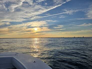 A serene sunset view from the deck of a boat, showcasing the tranquil waters and vibrant sky, perfect for evening cruises.
