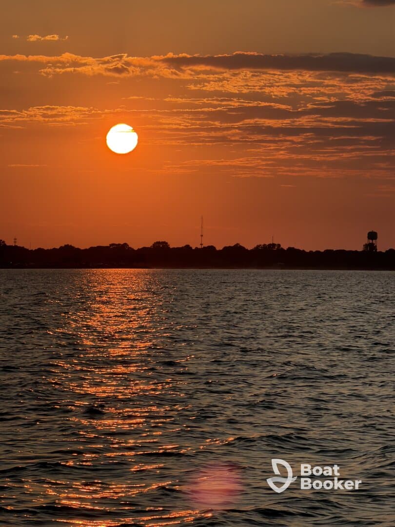 A stunning sunset casts a warm glow over the water, creating a picturesque scene perfect for evening boat cruises.