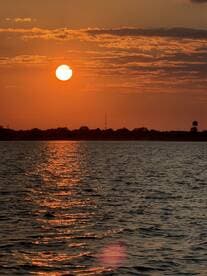 A stunning sunset casts a warm glow over the water, creating a picturesque scene perfect for evening boat cruises.