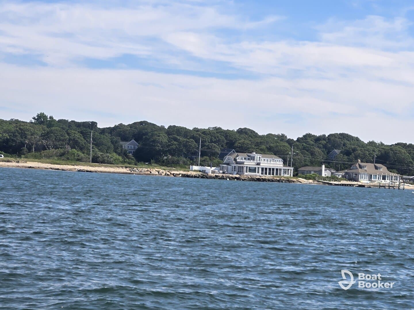 A picturesque view of a coastal shoreline with charming houses nestled among lush greenery, perfect for showcasing serene waterfront destinations.