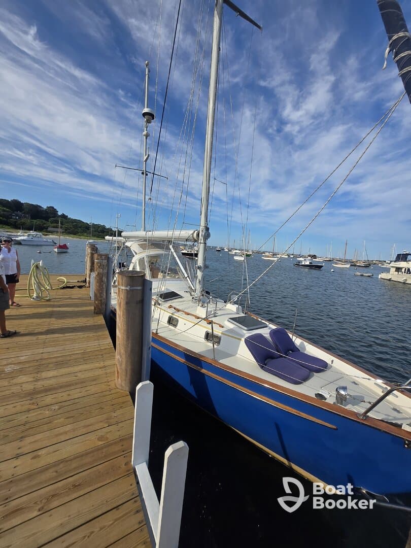 A beautiful blue sailboat docked at the marina, showcasing its elegant hull against a backdrop of clear skies and calm waters.