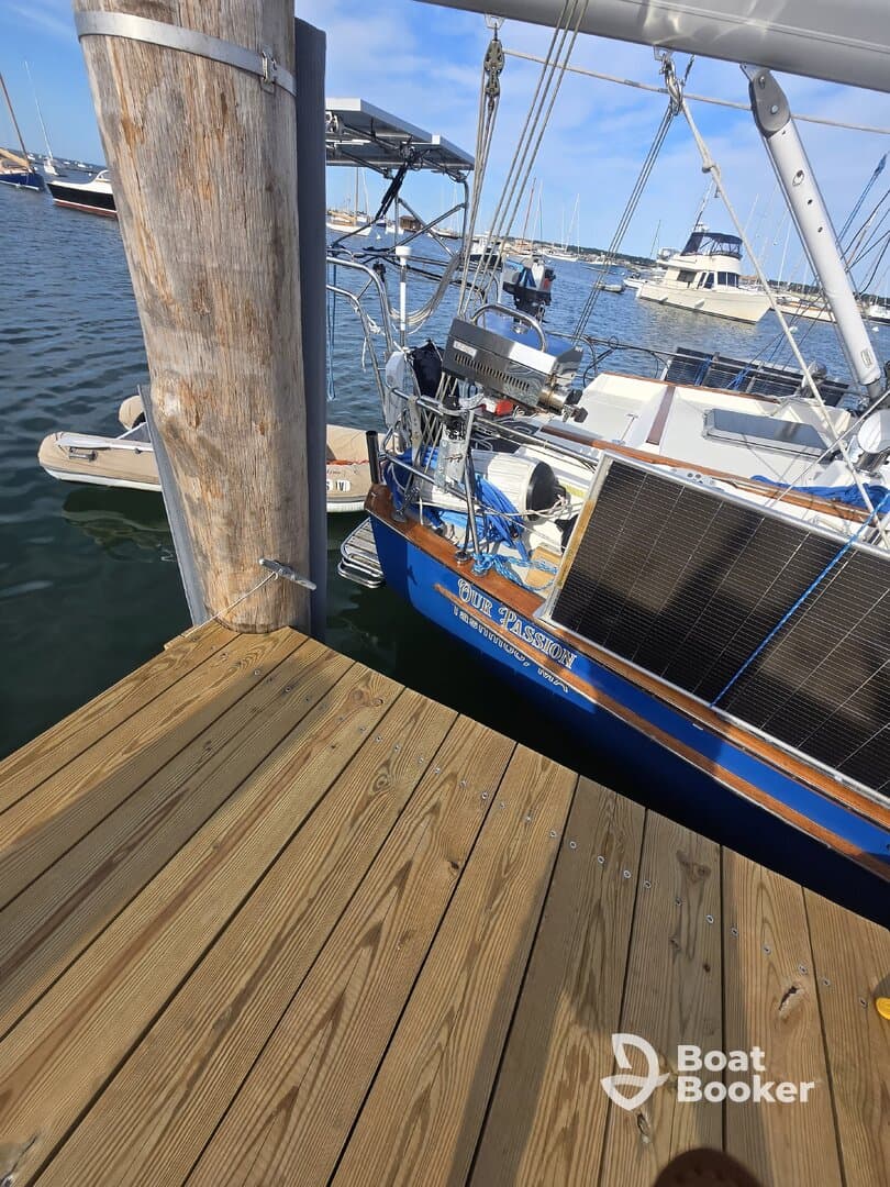 A close-up view of a sailboat named 'Our Passion' docked at the marina, showcasing its structure and surroundings.