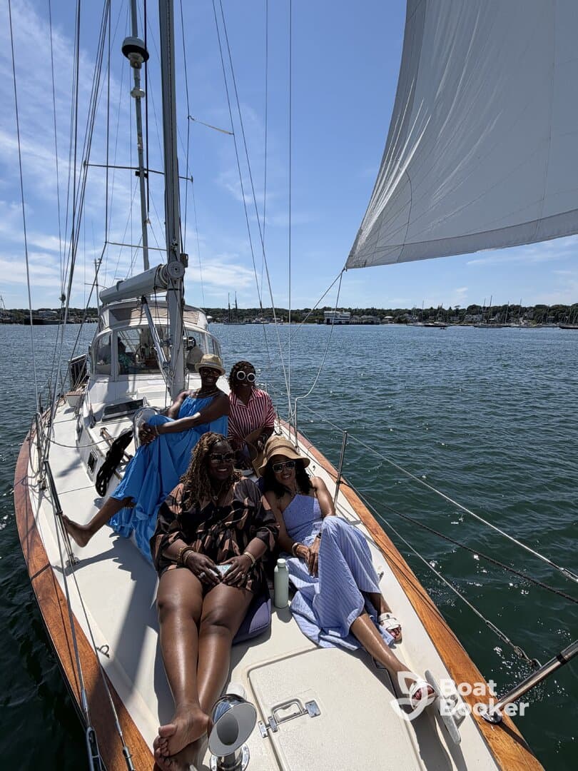 A joyful group of friends relaxes on the deck of a sailboat, enjoying a sunny day on the water — perfect for memorable sailing adventures.