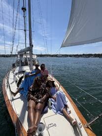 A joyful group of friends relaxes on the deck of a sailboat, enjoying a sunny day on the water — perfect for memorable sailing adventures.