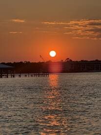 A stunning sunset casts a warm glow over the water, creating a picturesque reflection — perfect for capturing serene moments on the water.