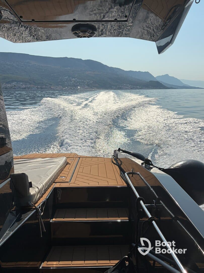 A sleek view from the back of a boat cruising through calm waters, showcasing the stunning reflections and surrounding mountains — perfect for adventure seekers and boating enthusiasts.