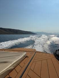 A stunning view from the deck of a boat cruising through calm waters, showcasing the sleek design and beautiful scenery in the background.