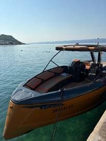 A sleek speedboat docked by the shore, showcasing its stylish design against a serene water backdrop — perfect for summer adventures.