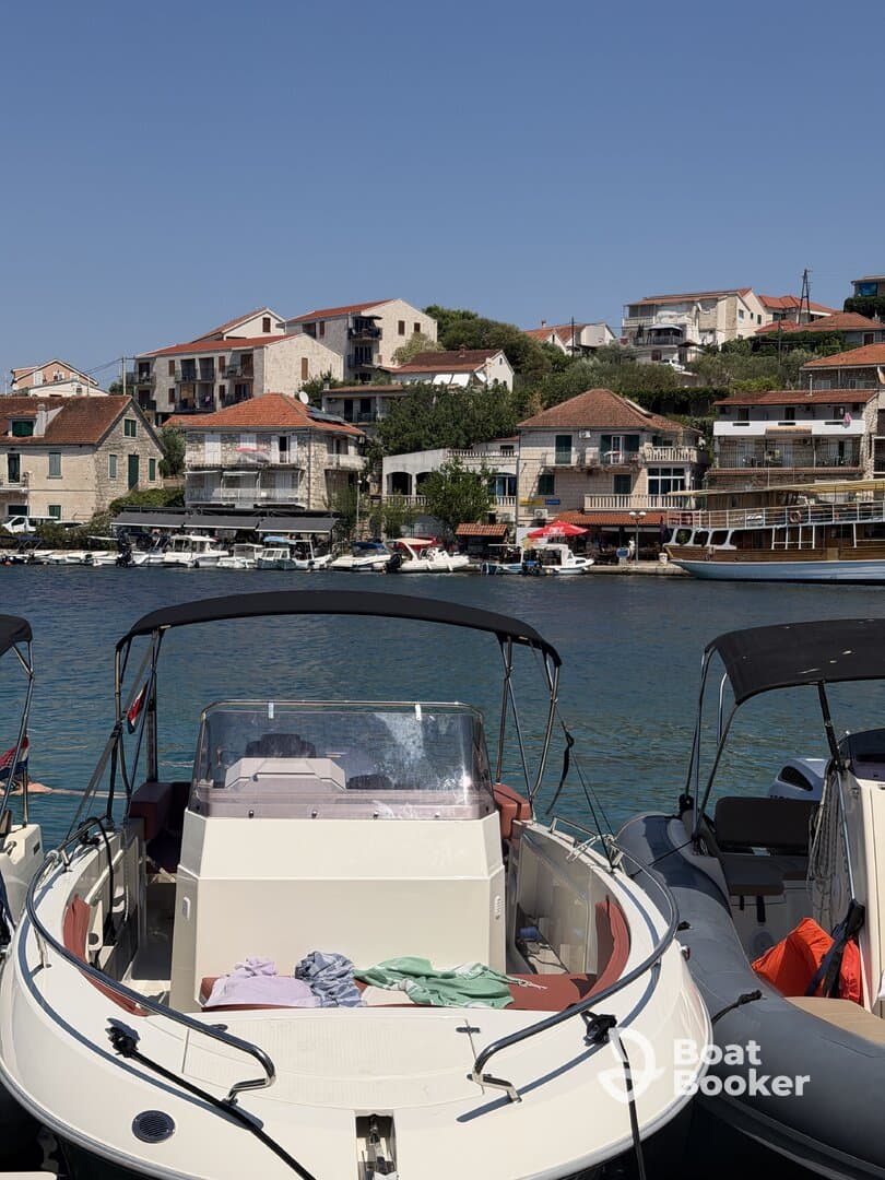 A close-up view of a boat docked in a picturesque harbor, showcasing its sleek design against a backdrop of charming coastal buildings.