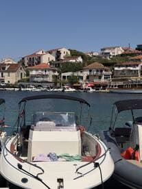 A close-up view of a boat docked in a picturesque harbor, showcasing its sleek design against a backdrop of charming coastal buildings.