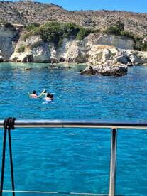 Two snorkelers enjoy the crystal-clear waters near a scenic coastline, perfect for underwater exploration and family adventures.