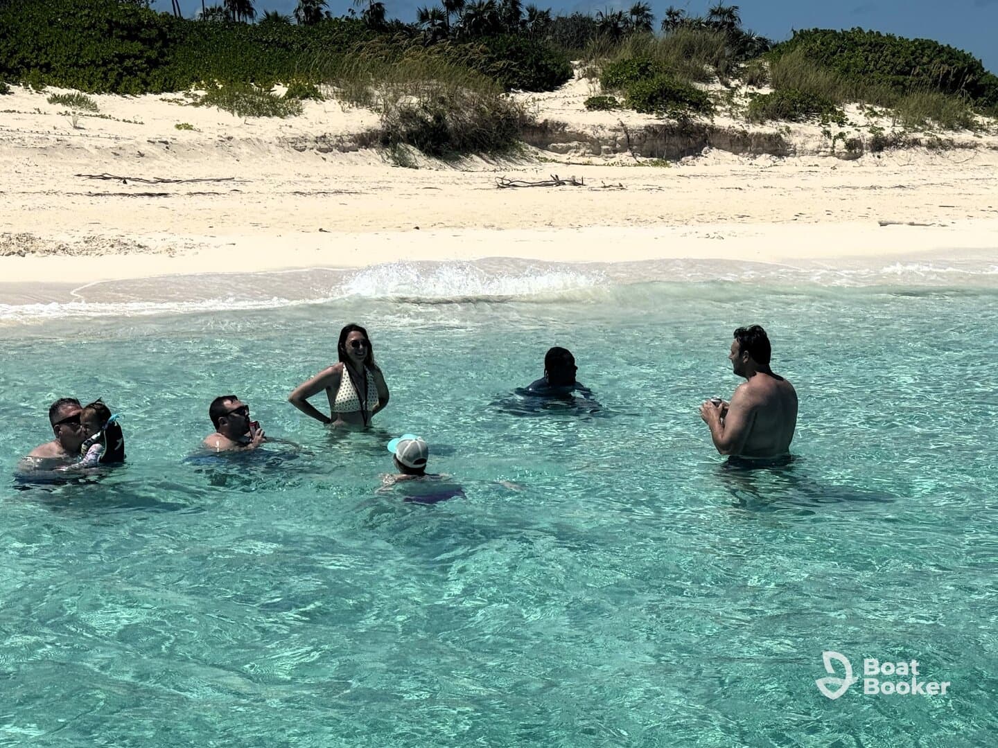 A lively group enjoys a refreshing swim in crystal-clear waters at the beach, creating unforgettable memories in a tropical paradise.