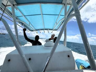 Crew members wave from the helm of a boat as it navigates through the ocean, showcasing the excitement of a day on the water.