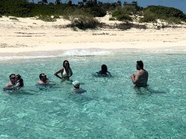 A lively group enjoys a refreshing swim in crystal-clear waters at the beach, creating unforgettable memories in a tropical paradise.