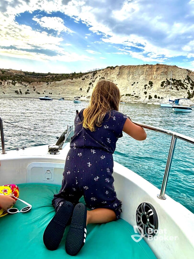 A child gazes out at the stunning coastline from the deck of a boat, capturing the essence of a memorable day on the water.