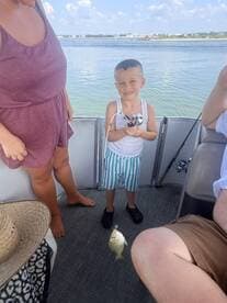 A young boy proudly displays his catch while fishing on a boat, creating cherished family memories on the water.