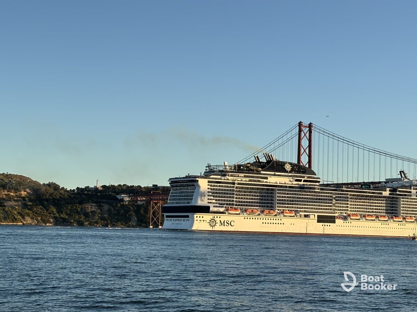 A majestic MSC cruise ship sails past the iconic bridge, showcasing its impressive structure against a clear sky — a perfect sight for maritime enthusiasts.