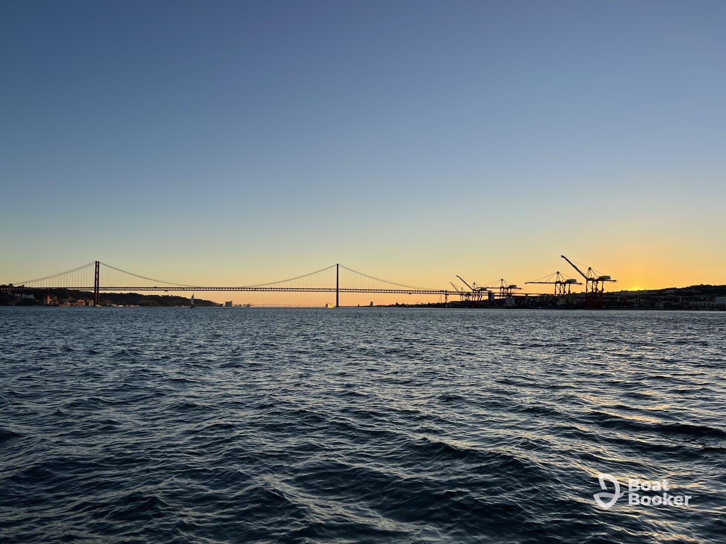 A stunning sunset view featuring a bridge silhouetted against the colorful sky, capturing the serene beauty of the waterfront.