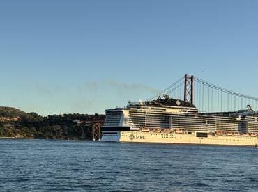 A majestic MSC cruise ship sails past the iconic bridge, showcasing its impressive structure against a clear sky — a perfect sight for maritime enthusiasts.