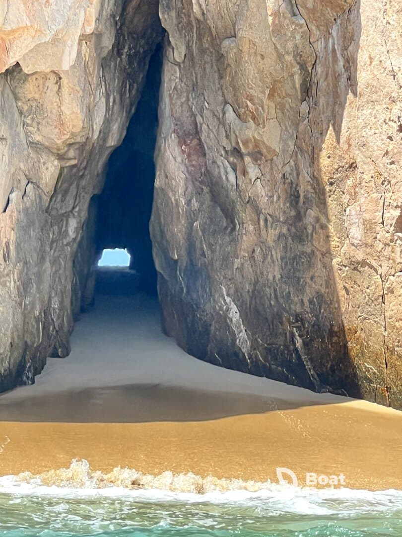 A stunning view of a natural cave opening on a sandy beach, showcasing the beautiful coastline and inviting turquoise waters — a perfect spot for exploration and adventure.