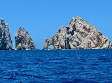 A stunning view of the iconic rock formations at Land's End in Cabo San Lucas, showcasing the natural beauty of the coastline against a vibrant blue sea.