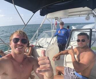 A group of friends enjoys a fun day on the boat, giving thumbs up and capturing the moment while cruising on the water.
