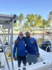 Two friends pose together on a boat, showcasing camaraderie and fun in a beautiful tropical setting — perfect for memorable boating adventures.