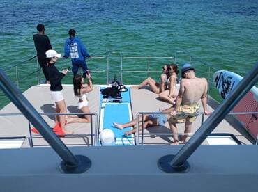 A lively group enjoys a sunny day on a pontoon boat, capturing moments and relaxing on the deck — perfect for summer parties and fun on the water.