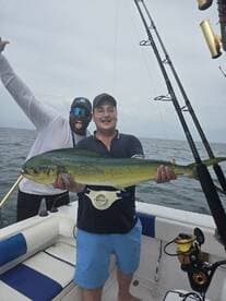 Two friends celebrate a successful fishing trip, proudly displaying their catch on a boat — a perfect moment for fishing enthusiasts.