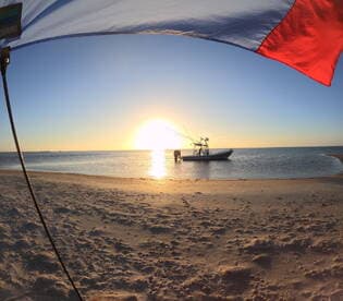 A picturesque sunset scene with a fishing boat anchored near the beach, as a person prepares for a day of fishing — a perfect blend of adventure and relaxation.
