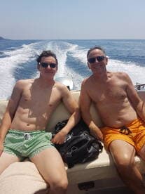 A father and son enjoy a sunny day on the boat, capturing a moment of relaxation and bonding on the water.