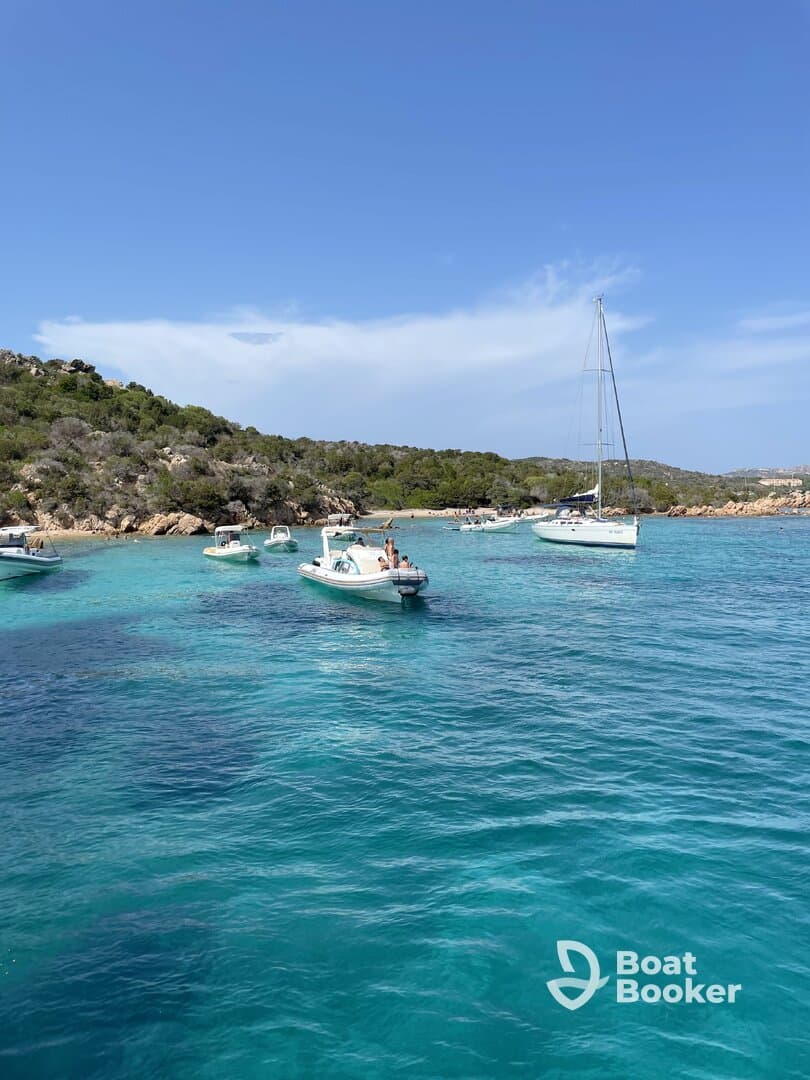 A scenic view of multiple boats anchored in crystal-clear turquoise waters near a beach, showcasing a perfect day for relaxation and water activities.