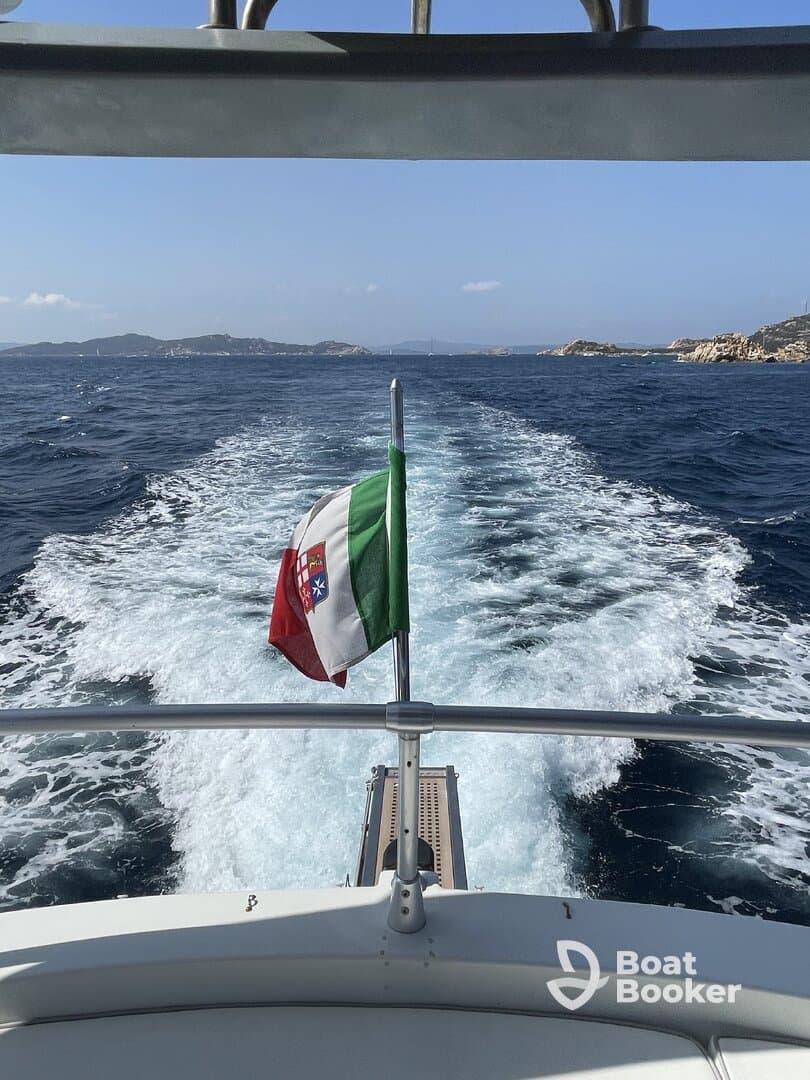 A view from the bow of a boat showcasing the Italian flag as it navigates through clear waters, perfect for scenic cruising or island hopping adventures.