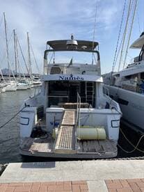 A clear view of the back of a yacht named 'Namès' docked at the marina, showcasing its structure and design against a backdrop of other boats.