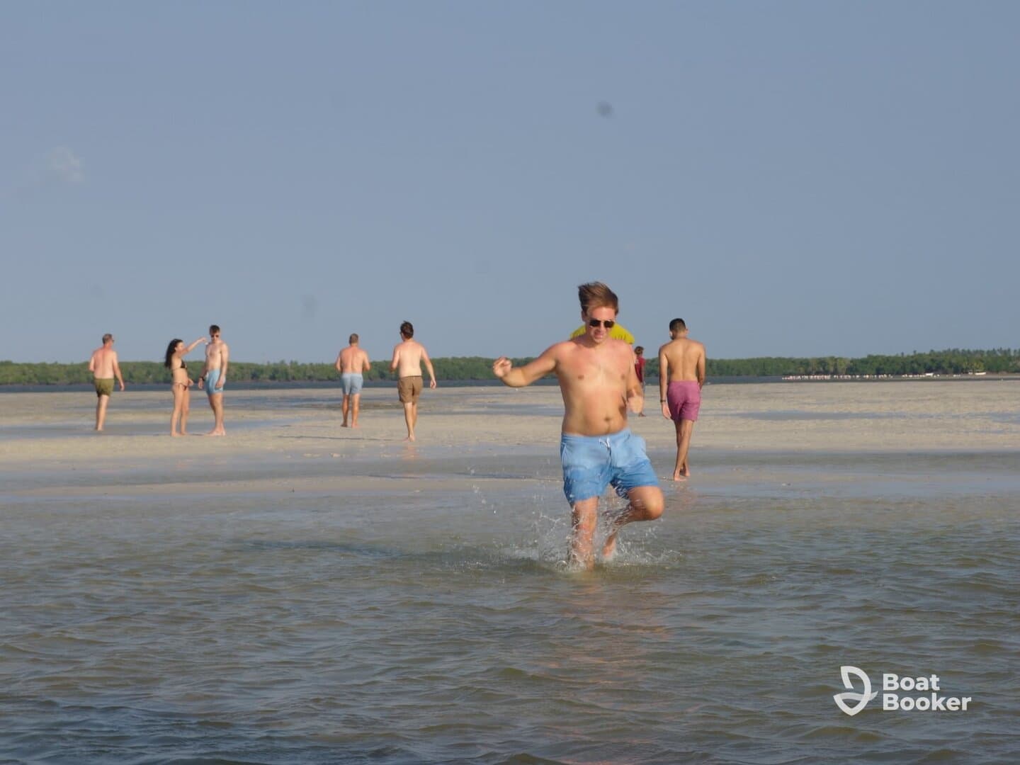 A lively group enjoys a fun day at the beach, splashing in the water and soaking up the sun during a sandbar stop.