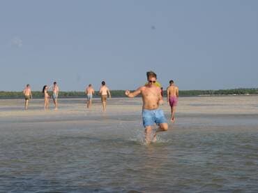 A lively group enjoys a fun day at the beach, splashing in the water and soaking up the sun during a sandbar stop.