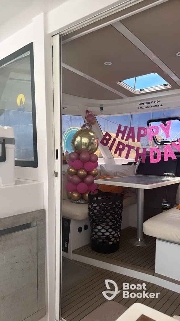 The interior of a boat is decorated for a birthday celebration, featuring festive balloons and a cheerful 'Happy Birthday' sign, creating a vibrant atmosphere for onboard festivities.