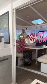 The interior of a boat is decorated for a birthday celebration, featuring festive balloons and a cheerful 'Happy Birthday' sign, creating a vibrant atmosphere for onboard festivities.