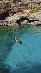 A child enjoys snorkeling in crystal-clear waters of a scenic cove, surrounded by vibrant marine life — a perfect family adventure in nature.