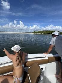 A young girl and an adult enjoy the scenic view from their boat, pointing towards the shoreline, capturing the essence of a fun day on the water.