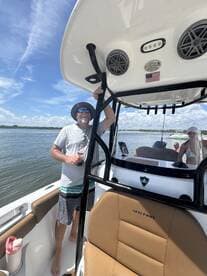 A man enjoys a sunny day on a boat, showcasing a relaxed atmosphere with friends in the background — perfect for summer outings on the water.