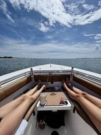 Two friends relax on the deck of a boat under the bright sun, enjoying a serene day on the water — perfect for unwinding and soaking up the sun.