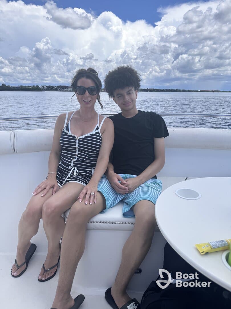A mother and her son enjoy a relaxing moment together on a boat, surrounded by beautiful water and clouds — perfect for family outings on the water.