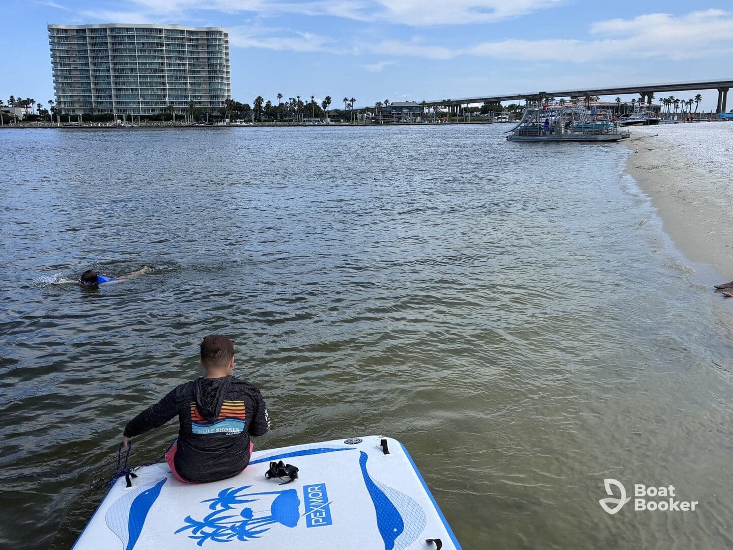 A fun day at the sandbar with a child swimming nearby while another person relaxes on a paddleboard, showcasing the perfect blend of water activities and family enjoyment.