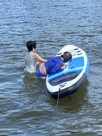 Two children enjoy paddleboarding in the water, showcasing a fun and active day on the water.