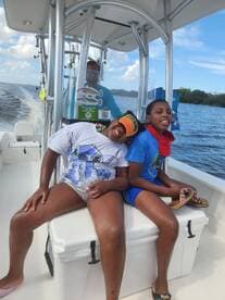 Two children enjoy a fun day on the boat, smiling and relaxing as they cruise through the water — a perfect family adventure.